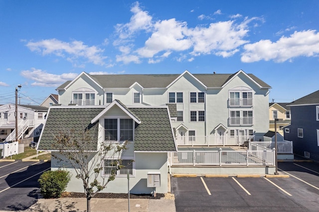 view of front of house featuring uncovered parking, a residential view, a tiled roof, and stucco siding