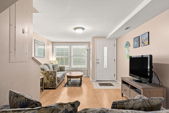 living area featuring light wood-type flooring, baseboards, electric panel, and visible vents