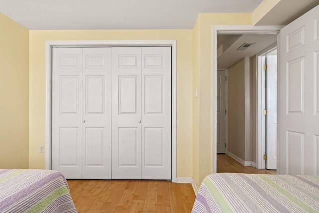 bedroom featuring light wood finished floors, a closet, visible vents, and baseboards