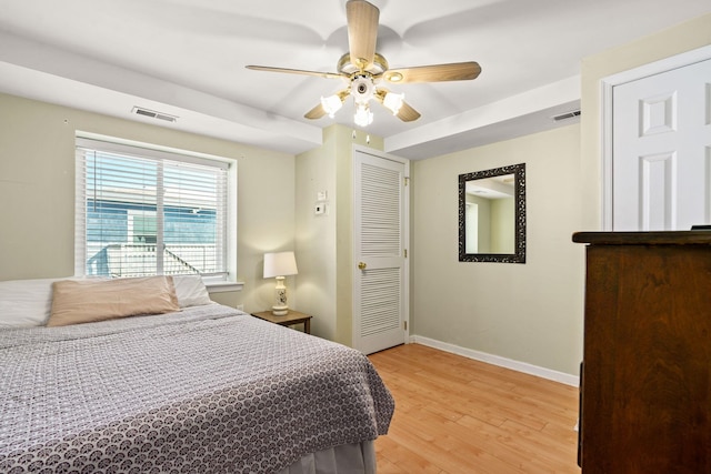 bedroom featuring baseboards, a ceiling fan, visible vents, and light wood-style floors