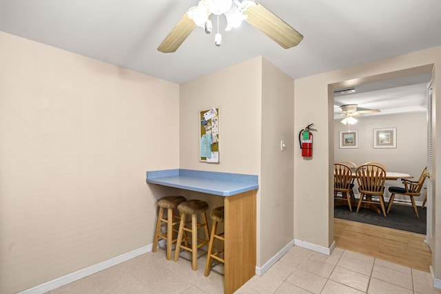 interior space featuring light tile patterned floors, a ceiling fan, and baseboards