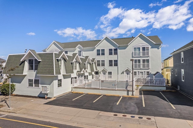 view of building exterior with uncovered parking, fence, and a residential view