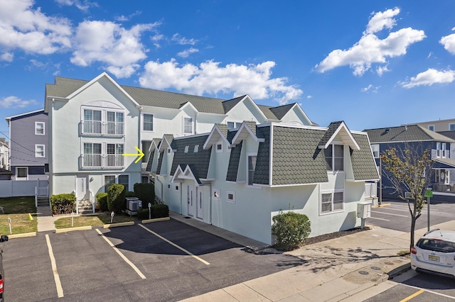 view of front of house with uncovered parking, a tiled roof, a residential view, and stucco siding