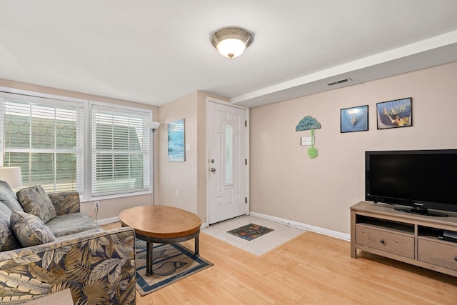 living area with visible vents, light wood-style flooring, and baseboards