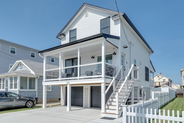 beach home with stairs, fence, driveway, a porch, and a garage