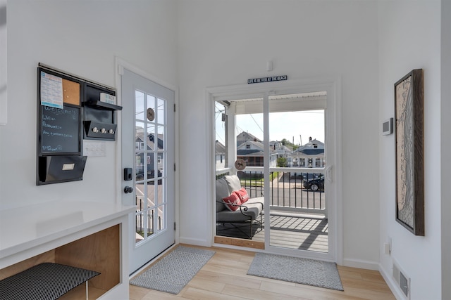 doorway to outside with baseboards, wood finished floors, and visible vents