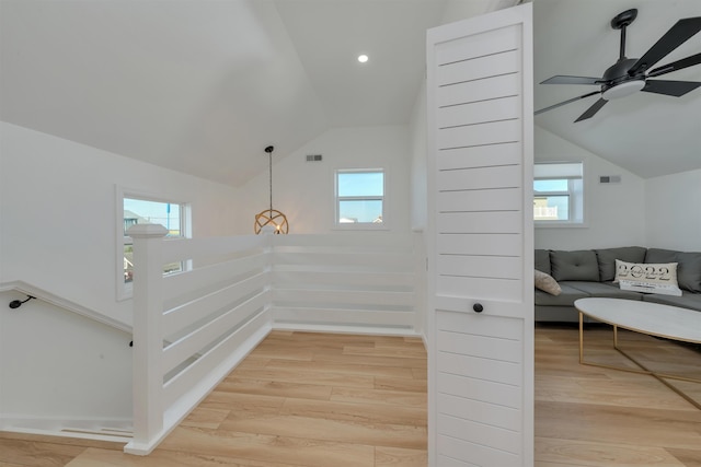 interior space with vaulted ceiling, a wealth of natural light, a ceiling fan, and wood finished floors