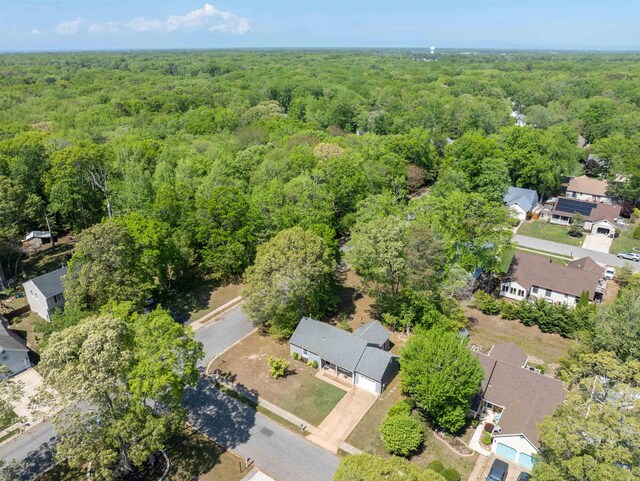 aerial view of property and surrounding area featuring a forest and nearby suburban area