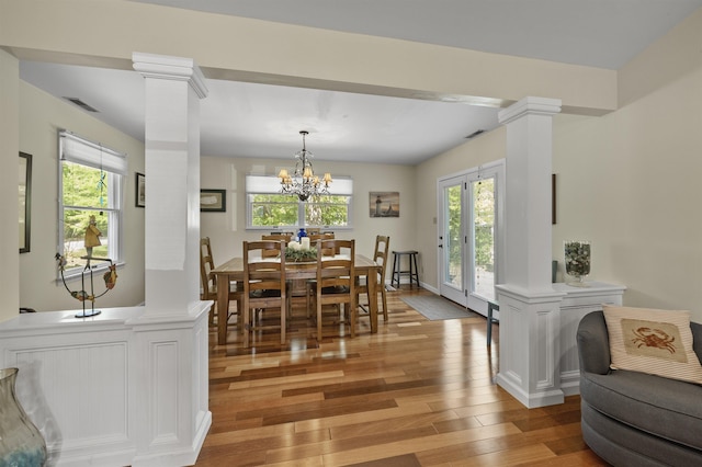 dining area featuring ornate columns, light wood finished floors, and healthy amount of natural light