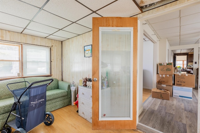 interior space with hardwood / wood-style flooring, a paneled ceiling, and wood walls