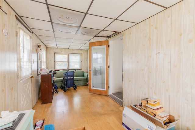 office with light wood-type flooring, a paneled ceiling, and wood walls