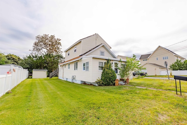 rear view of house with a lawn and a storage unit