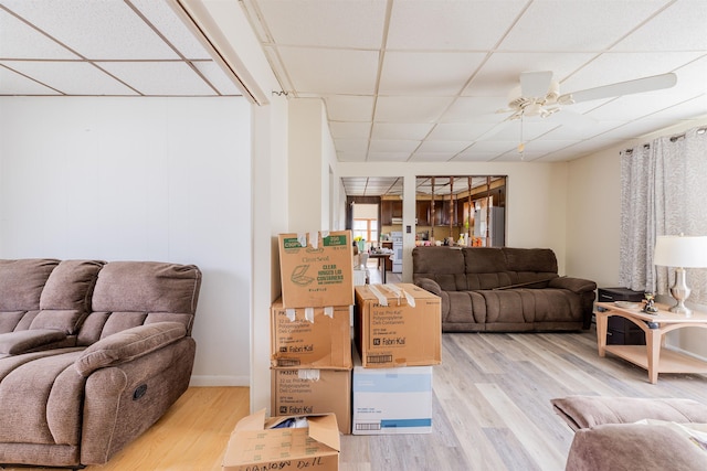 living room featuring ceiling fan, a drop ceiling, and wood-type flooring