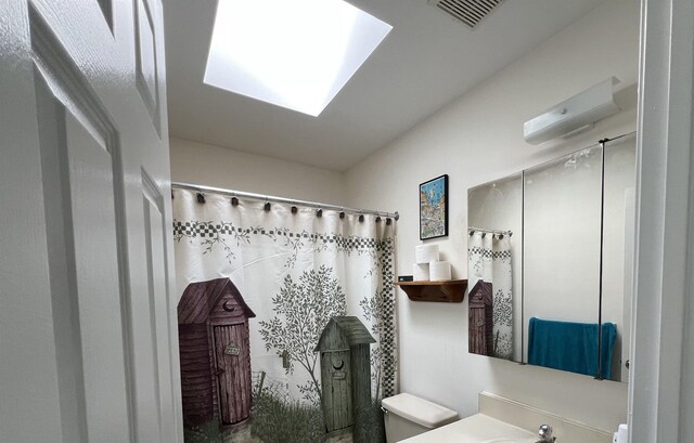 bathroom featuring a skylight, visible vents, toilet, a shower with curtain, and vanity