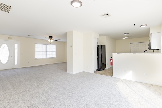 unfurnished living room featuring light colored carpet and ceiling fan