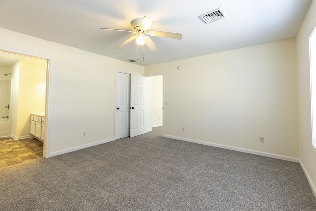 unfurnished bedroom featuring ceiling fan, carpet floors, and ensuite bath