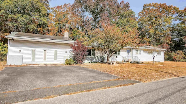 ranch-style house with a front lawn, driveway, and a chimney