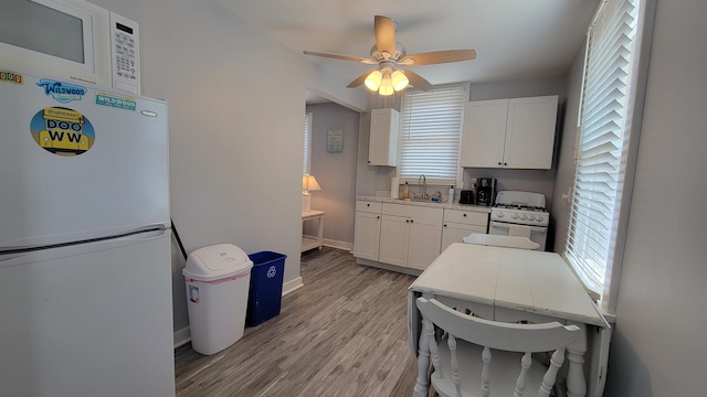 kitchen featuring ceiling fan, sink, white appliances, white cabinets, and light wood-type flooring