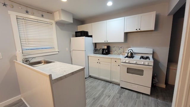 kitchen with sink, white cabinets, light hardwood / wood-style floors, and white appliances