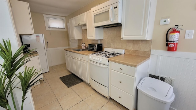 kitchen with white cabinetry, white appliances, sink, and light tile patterned floors