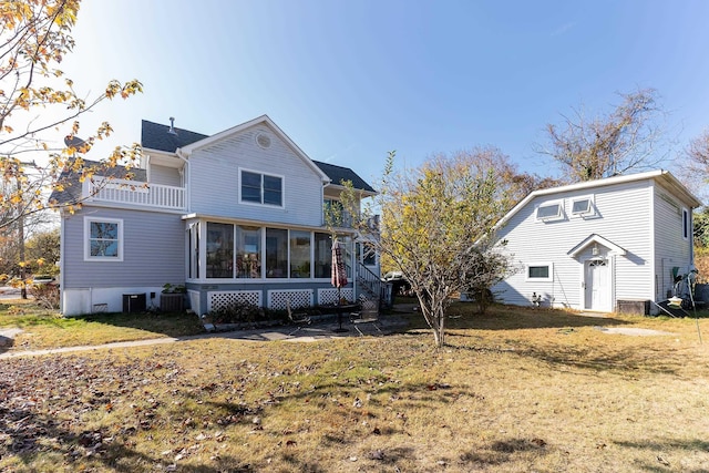 back of property featuring a balcony, a sunroom, and a yard