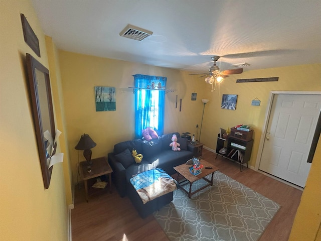 living room featuring baseboards, ceiling fan, visible vents, and wood finished floors