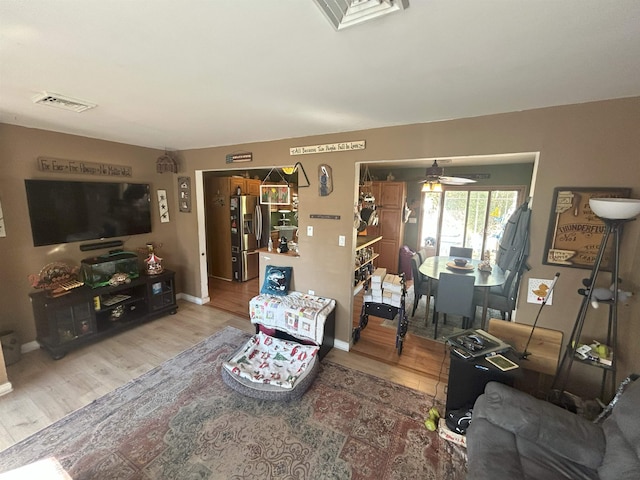 living room with a ceiling fan, baseboards, visible vents, and wood finished floors