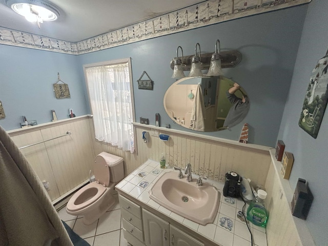 bathroom with toilet, a wainscoted wall, a baseboard radiator, tile patterned floors, and vanity