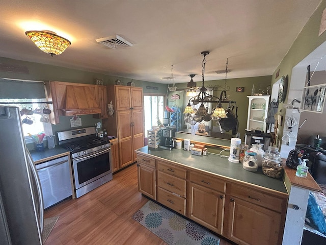 kitchen featuring brown cabinetry, visible vents, stainless steel appliances, and pendant lighting