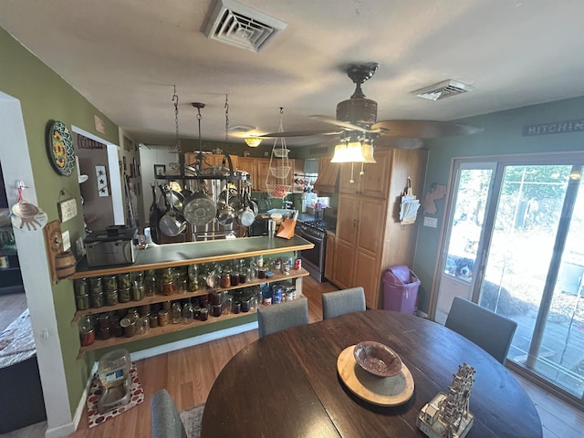 dining space featuring a ceiling fan, visible vents, and wood finished floors