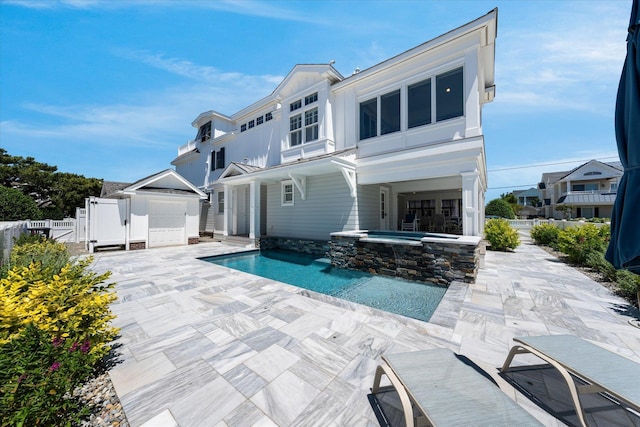 rear view of property featuring a patio area and a pool with hot tub