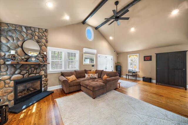 2068 N Shore Rd, Clermont, NJ 08210 - living room featuring a wall mounted air conditioner, a ceiling fan, beamed ceiling, wood finished floors, and a stone fireplace