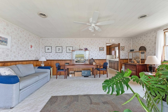 living room featuring wood walls, ceiling fan, and light colored carpet