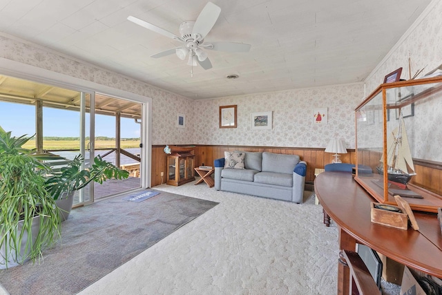 living room featuring carpet, ceiling fan, and a water view