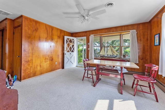 carpeted dining room featuring ceiling fan and wooden walls