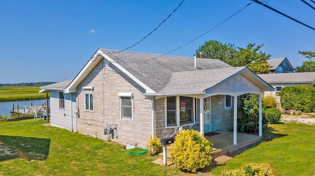 rear view of property featuring a lawn and a water view