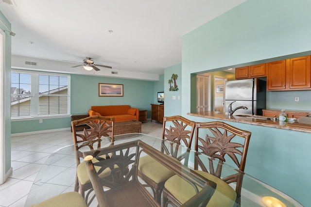 tiled dining area featuring ceiling fan and sink