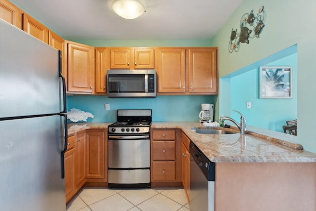 kitchen featuring sink, light stone counters, kitchen peninsula, light tile patterned floors, and appliances with stainless steel finishes