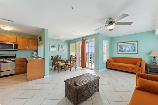 tiled living room with ceiling fan and sink