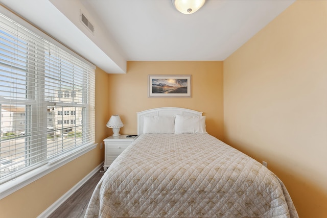 bedroom with multiple windows and dark wood-type flooring