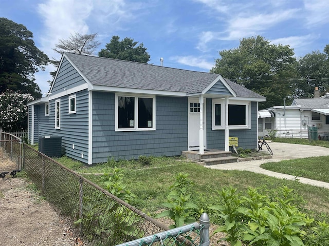 bungalow with a front yard and central air condition unit