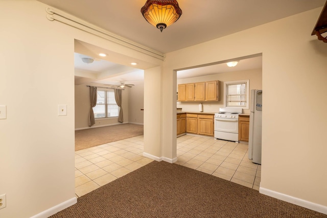 kitchen with ceiling fan, light brown cabinetry, light colored carpet, and white appliances