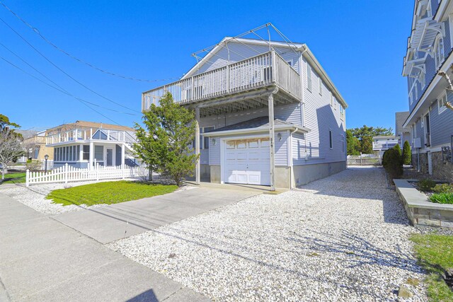 view of front facade with a balcony, a garage, fence, and driveway