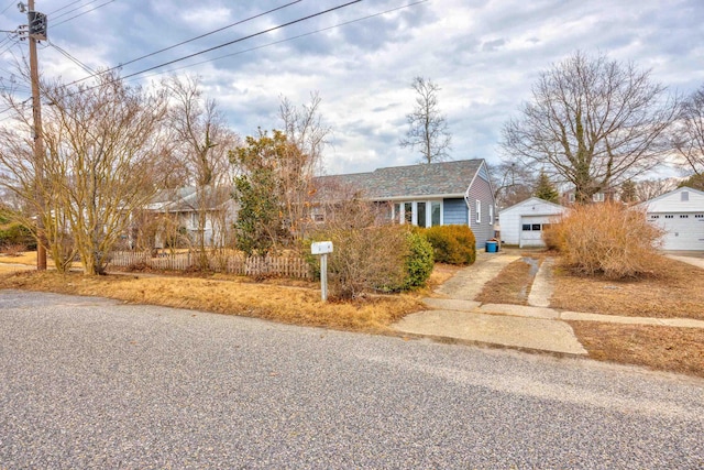 view of front of home with a detached garage, concrete driveway, and an outbuilding