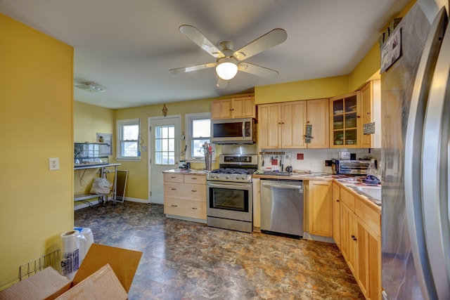 kitchen featuring appliances with stainless steel finishes, backsplash, light brown cabinets, and glass insert cabinets