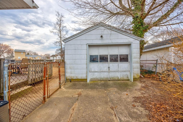 detached garage with driveway, fence, and a gate