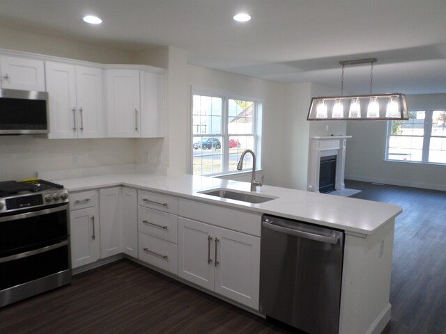 kitchen with stainless steel appliances, kitchen peninsula, sink, and white cabinets