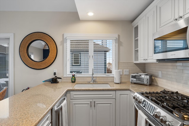 13 93rd St Unit 5, Stone Harbor, NJ 08247 - kitchen with stainless steel appliances, tasteful backsplash, white cabinetry, light stone counters, and glass insert cabinets