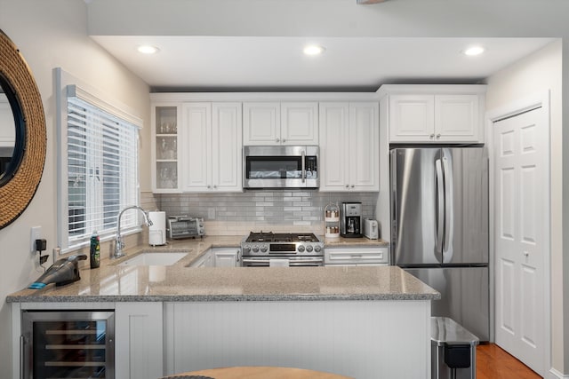13 93rd St Unit 5, Stone Harbor, NJ 08247 - kitchen featuring stainless steel appliances, wine cooler, light stone countertops, a peninsula, and backsplash