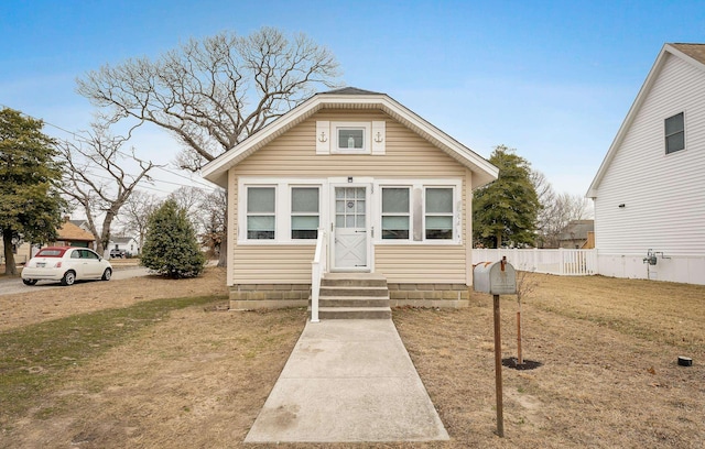 bungalow-style house featuring entry steps, fence, and a front yard